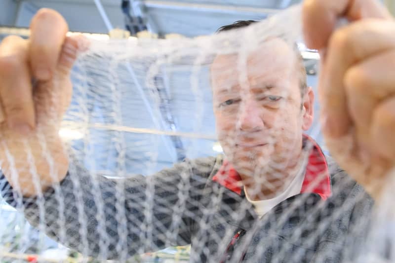 Thomas Hartung, managing director of Mesh Pack, tests a biodegradable net for bagging fruit or vegetables in the production hall. Klaus-Dietmar Gabbert/dpa