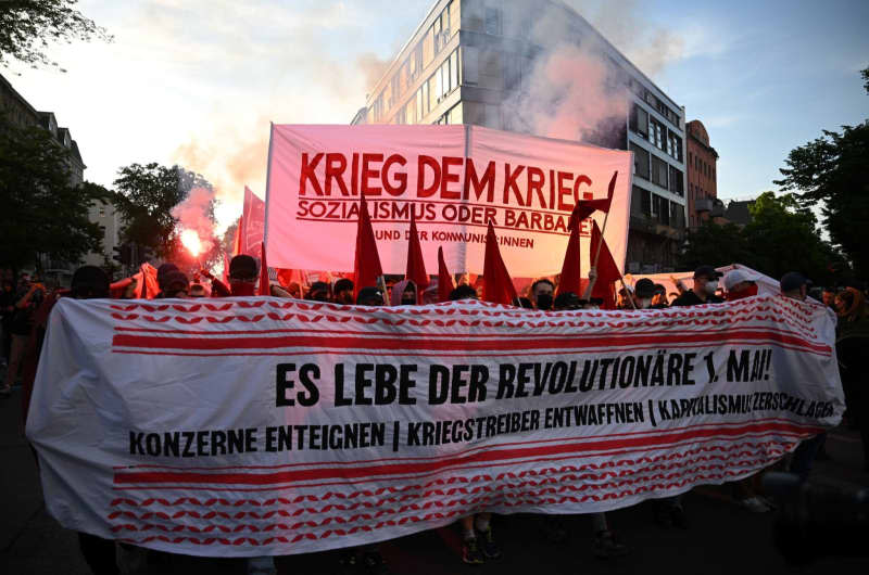 People hold up a banner with the words "War on War" and set off pyrotechnics during the "Revolutionary May Day Demonstration". Sebastian Gollnow/dpa