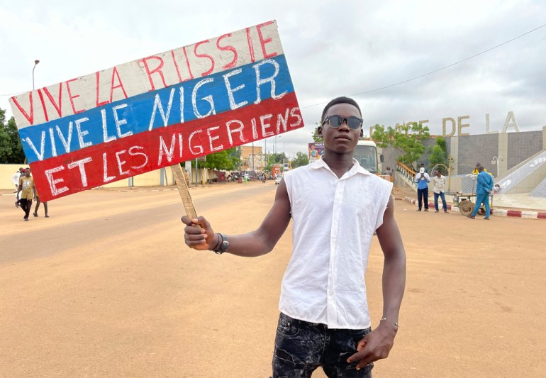 A supporter of Niger's ruling junta holds a placard in the colors of the Russian flag reading "Long Live Russia, Long Live Niger and Nigeriens" 